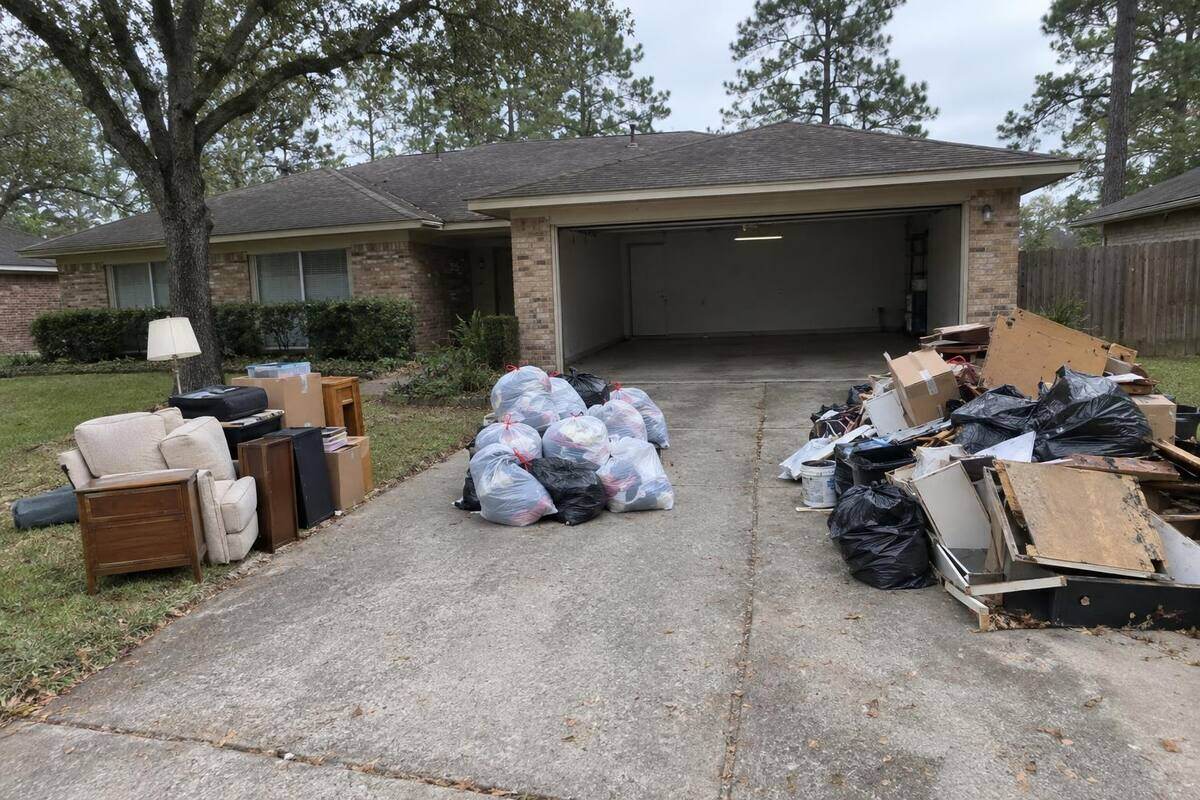 A driveway with three loose piles of household things, a garage door open behind them