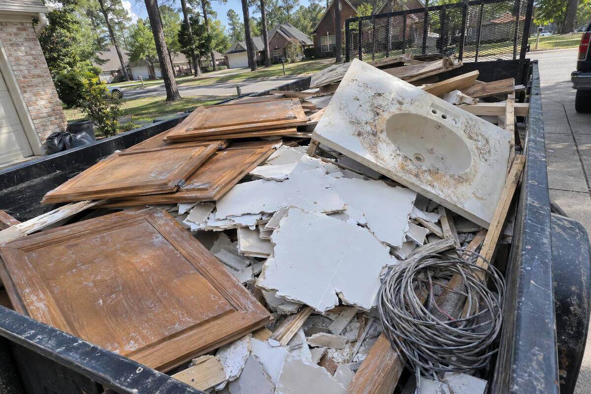 Broken drywall pieces, old cabinet doors and lumber scraps piled in an open trailer bed